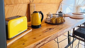 A compact kitchen with a wooden table, yellow kettle, and a toaster.