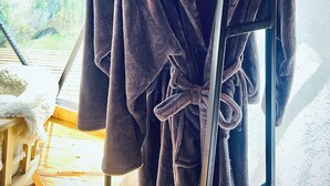 A wooden rack with two bathrobes hanging on it.