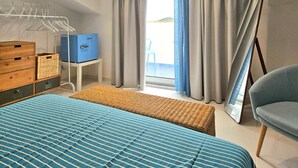 A bedroom with a bed, a wooden dresser, a blue storage box, a wicker bench, and a chair. - Stunning apartment in Santa Maria di C.te, C (Santa Maria di C.te, C)