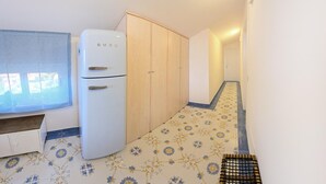 A narrow hallway with a white refrigerator, wooden wardrobe, and a patterned floor. - Stunning apartment in Santa Maria di C.te, C (Santa Maria di C.te, C)