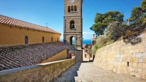 A historic stone tower with a clock, a yellow building with tiled roof, and a stone wall. - Stunning apartment in Santa Maria di C.te, C (Santa Maria di C.te, C)