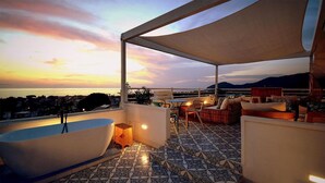 A rooftop terrace with a bathtub, outdoor seating, and a view of the city at sunset. - Stunning apartment in Santa Maria di C.te, C (Santa Maria di C.te, C)
