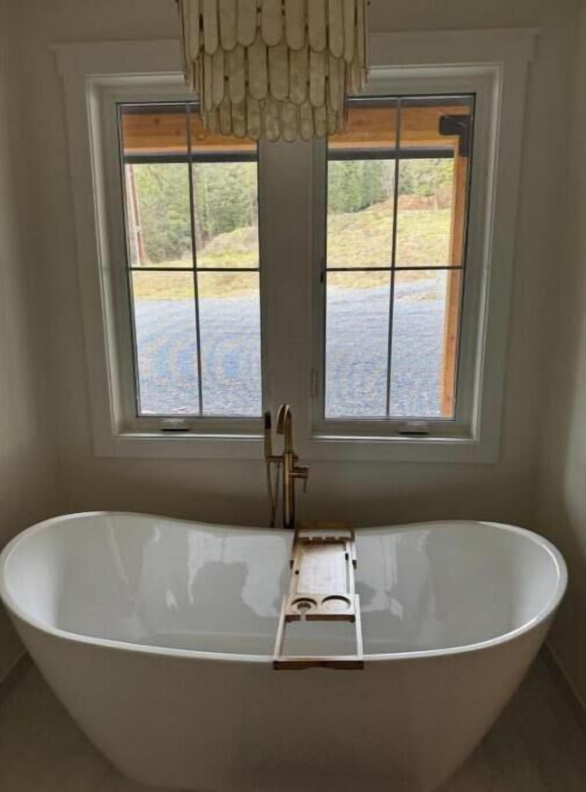 A bathroom with a freestanding bathtub, a window with a view of a paved area, and a towel rack.