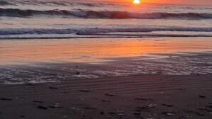 Une plage avec des vagues et un coucher de soleil.