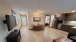 A modern apartment with a dining area, kitchen, and living space. - Jack Pine Cabin at Pine Ridge Park (Pembroke)