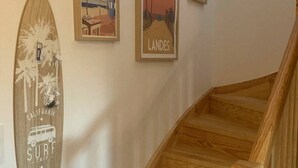 A wooden staircase with a surfboard and two framed posters on the wall. - Les Fougères - Moliets (MOLIETS ET MAA)