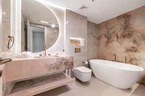 A modern bathroom with a freestanding bathtub, a vanity with a large mirror, and a toilet. - Luxury Villa with Pool and Garden 4BR The Springs (Dubai)