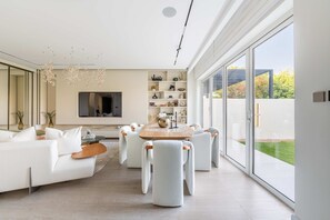 Una sala moderna con un sofá blanco, una mesa redonda de madera y sillas a juego.