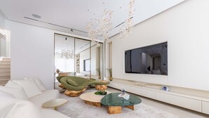 Ein modernes Wohnzimmer mit einer Couch, einem Couchtisch und einem an der Wand montierten Fernseher.