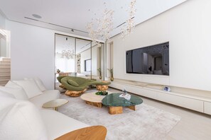 A modern living room with a sofa, coffee table, and a TV mounted on the wall. - Luxury Villa with Pool and Garden 4BR The Springs (Dubai)