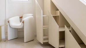 Un interior modern amb una escala minimalista, una cadira blanca i una taula petita.