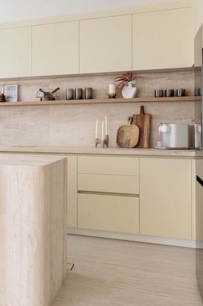 A modern kitchen with light-colored cabinets, a countertop with various items including a coffee maker, a cutting board, and decorative vases. - Luxury Villa with Pool and Garden 4BR The Springs (Dubai)