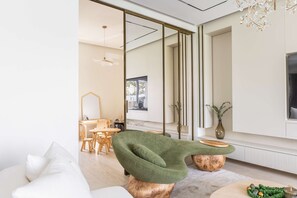 A modern living room with a green armchair, wooden coffee table, and a dining area with wooden chairs and a table. - Luxury Villa with Pool and Garden 4BR The Springs (Dubai)