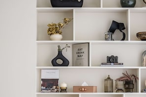 A neatly organized shelf with decorative items, books, and a camera. - Luxury Villa with Pool and Garden 4BR The Springs (Dubai)