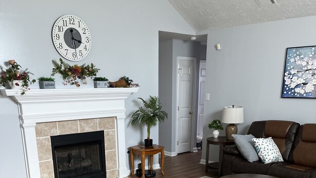 A living room with a fireplace, a clock, a couch, a coffee table, and a rug. - Prime Location! 3BR/2BA house near [National Hills] in beautiful Augusta! (Augusta)