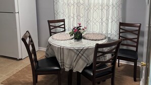 A dining area with a round table, four chairs, a small plant, and a patterned curtain. - Prime Location! 3BR/2BA house near [National Hills] in beautiful Augusta! (Augusta)