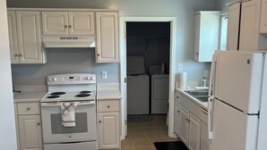A kitchen with white cabinets, a stove, a refrigerator, and a laundry area. - Prime Location! 3BR/2BA house near [National Hills] in beautiful Augusta! (Augusta)