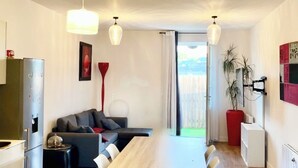 A modern kitchen with a wooden dining table, white chairs, and a red floor lamp.