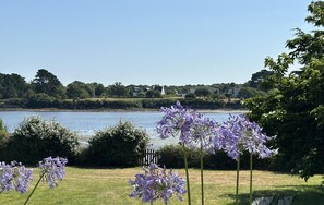 Vista de un lago con flores moradas en primer plano y un letrero que señala un atractivo turístico.