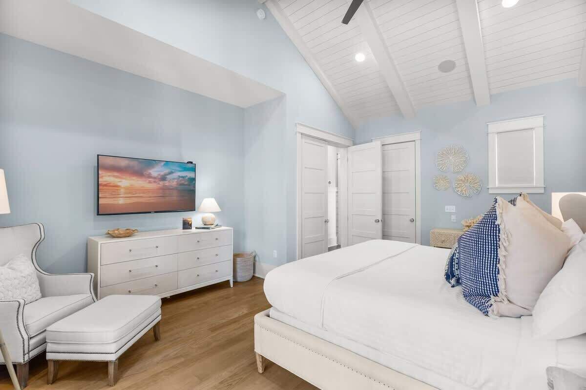 A bedroom with a bed, a dresser, a TV, and a ceiling fan.