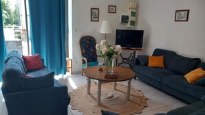 Un salón con sofá, sillón, mesa de centro, televisor y una obra de arte en la pared.