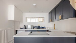 Una cocina moderna con una isla central, armarios oscuros y un ventanal sobre el fregadero.