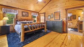 Une chambre dans une cabane en bois, avec un lit, une commode et un ventilateur de plafond.