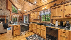 Une cuisine de style rustique, aménagée comme une cabane, avec des meubles en bois, un mur en pierre et une cheminée.