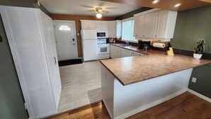 A modern kitchen with white cabinets, a wooden countertop, and a ceiling fan. - Lake Escape 1-minute walk to beach/Main st (Winnipeg Beach)