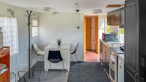 Une cuisine compacte comprenant un coin repas, une petite table avec des chaises et un réfrigérateur.