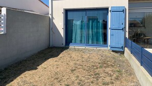 Un pequeño edificio de una sola planta con techo de tejas, puerta corrediza de vidrio y pared de concreto.