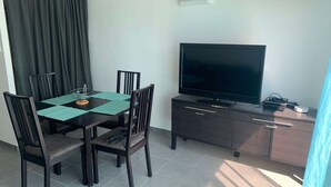 Comedor con una mesa, sillas, un televisor de pantalla plana y un armario.