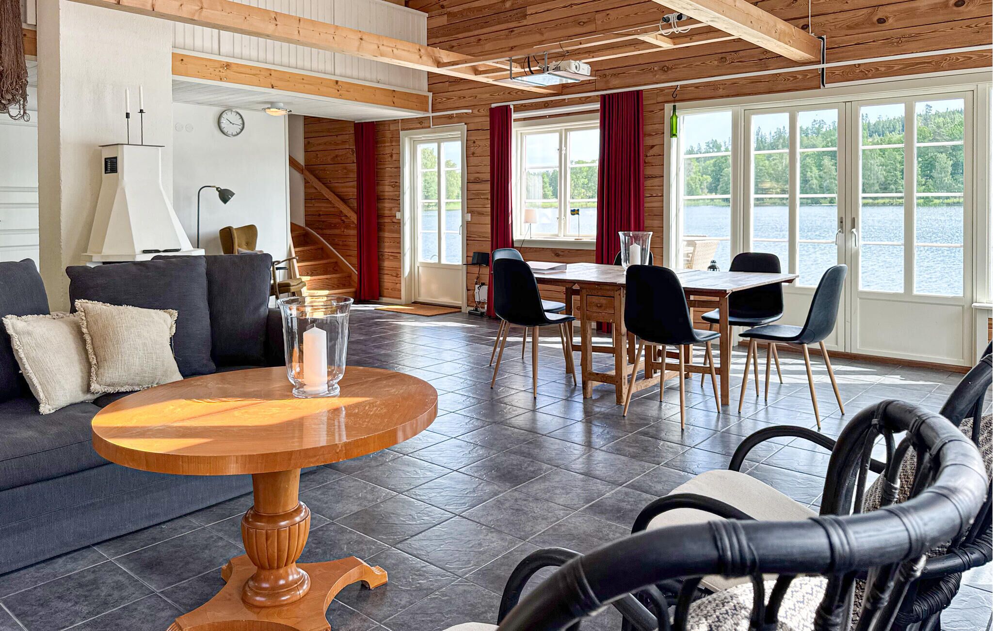 A spacious living area with a wooden ceiling, a round wooden table, a sofa, and a dining table with chairs.
