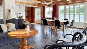 A spacious living area with a wooden ceiling, a round wooden table, a sofa, and a dining table with chairs. - Lovely home in Gränna with house sea view (Gränna)