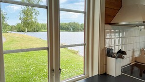 A kitchen with a view of a lake, a wooden ceiling, and a utensil holder on the counter. - Lovely home in Gränna with house sea view (Gränna)