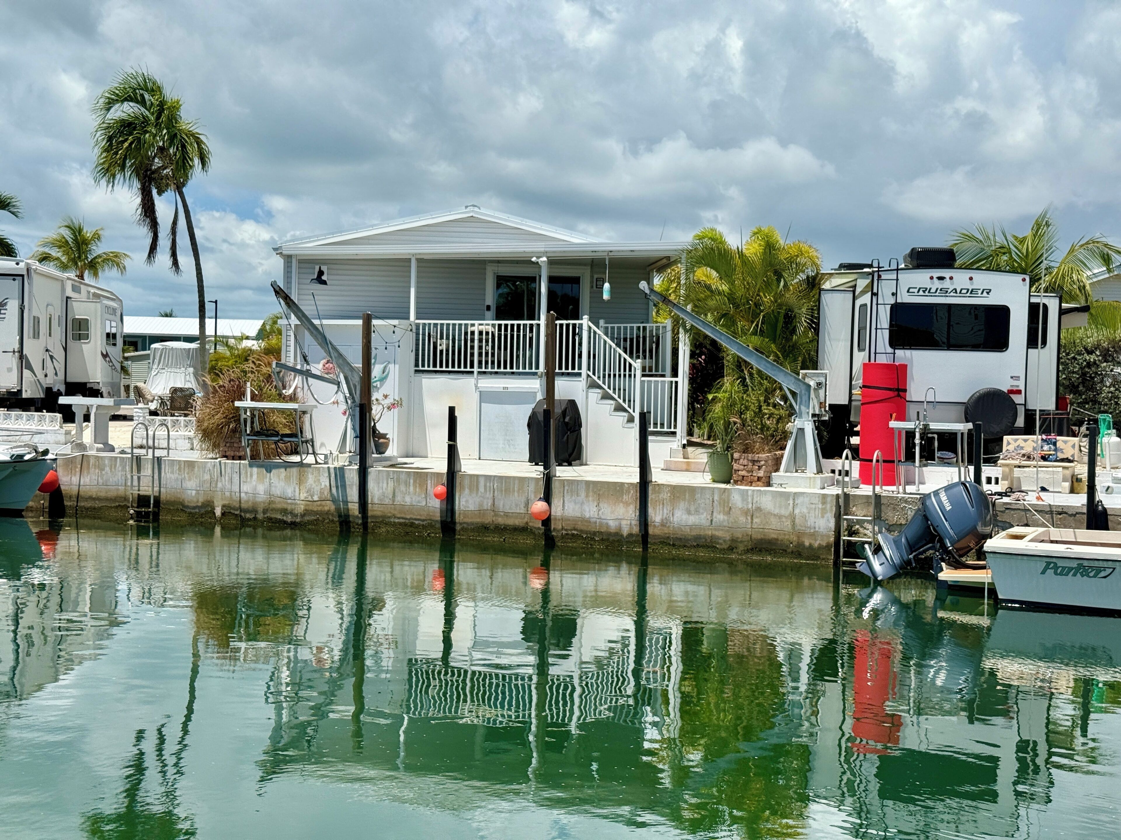 A waterfront property with a house, a dock, and a parked RV.