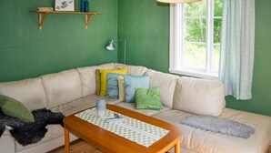 A living room with a beige sofa, a wooden coffee table, and a window with curtains. - Cozy home in Närkesberg (Närkesberg)