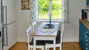 A kitchen with a dining table, chairs, a window with curtains, and a microwave. - Cozy home in Närkesberg (Närkesberg)