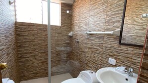 Une salle de bain comprenant des toilettes, un lavabo et un espace douche.