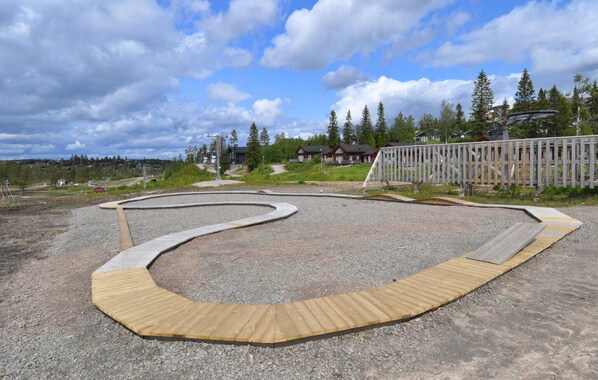 A wooden deck with a curved design, surrounded by gravel and a wooden fence.