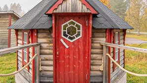 Eine Blockhütte mit roter Tür und einem sechseckigen Fenster.
