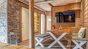 Ein gemütliches Blockhaus-Interieur mit Steinwand, Holzwänden, einem Holztisch und einer Bank.