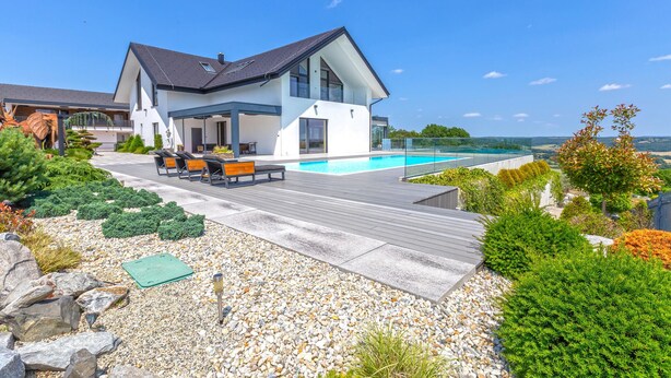 Ein modernes Haus mit Schwimmbad, Sitzgelegenheit im Freien und Blick auf die Landschaft.