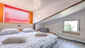 Une chambre à coucher avec un lit, des oreillers, une fenêtre et un radiateur.