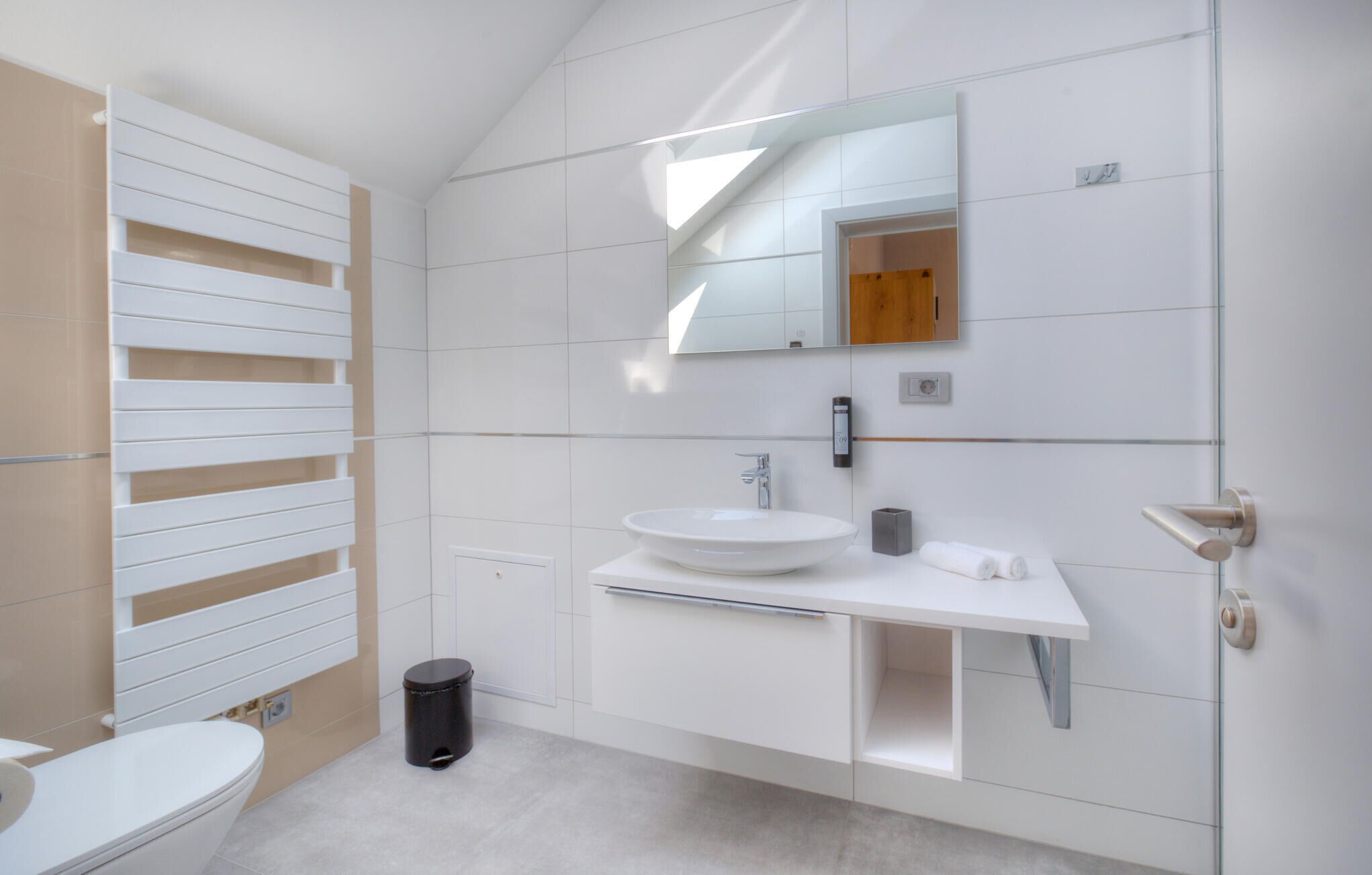 Ein modernes Badezimmer mit Waschbecken, Spiegel und Toilette in Weiß.