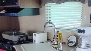 Une cuisine compacte dotée d’armoires en bois, d’un four à micro-ondes, d’une cuisinière, d’un évier et d’un grille-pain.