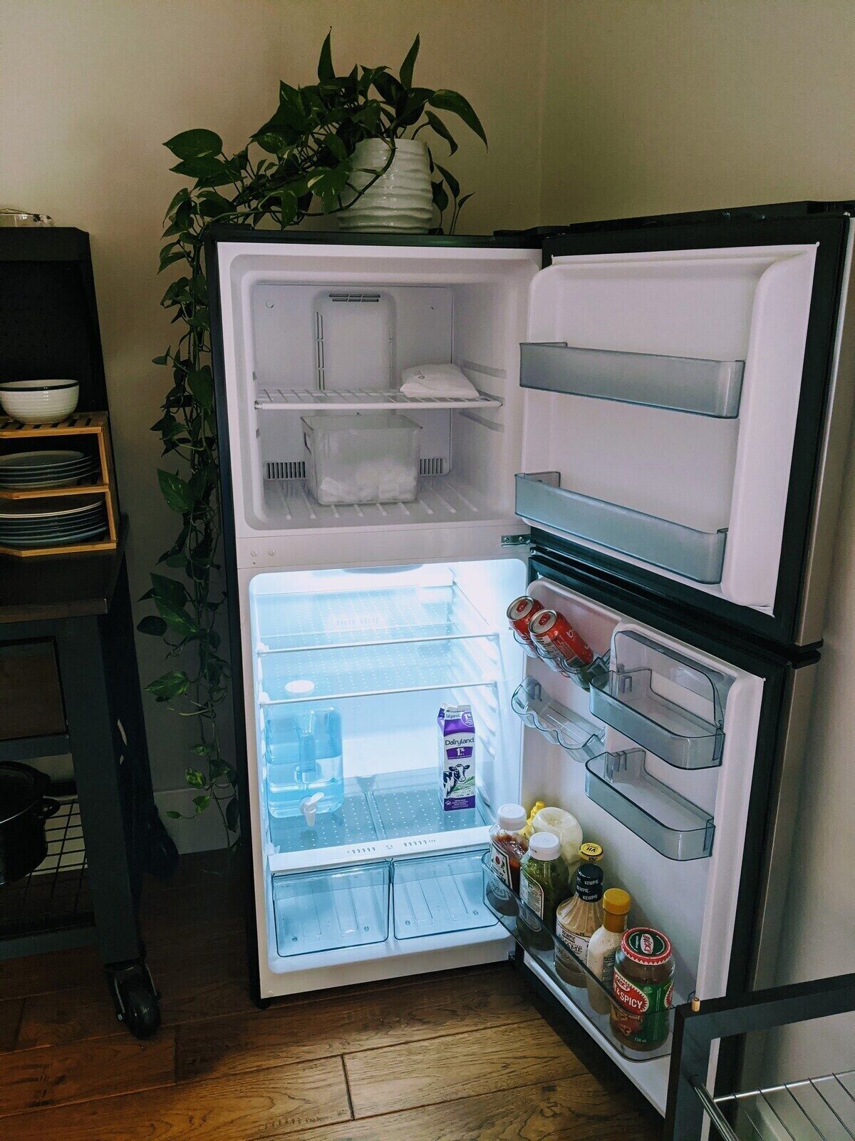 An open refrigerator with shelves and compartments, a milk carton, and condiments.
