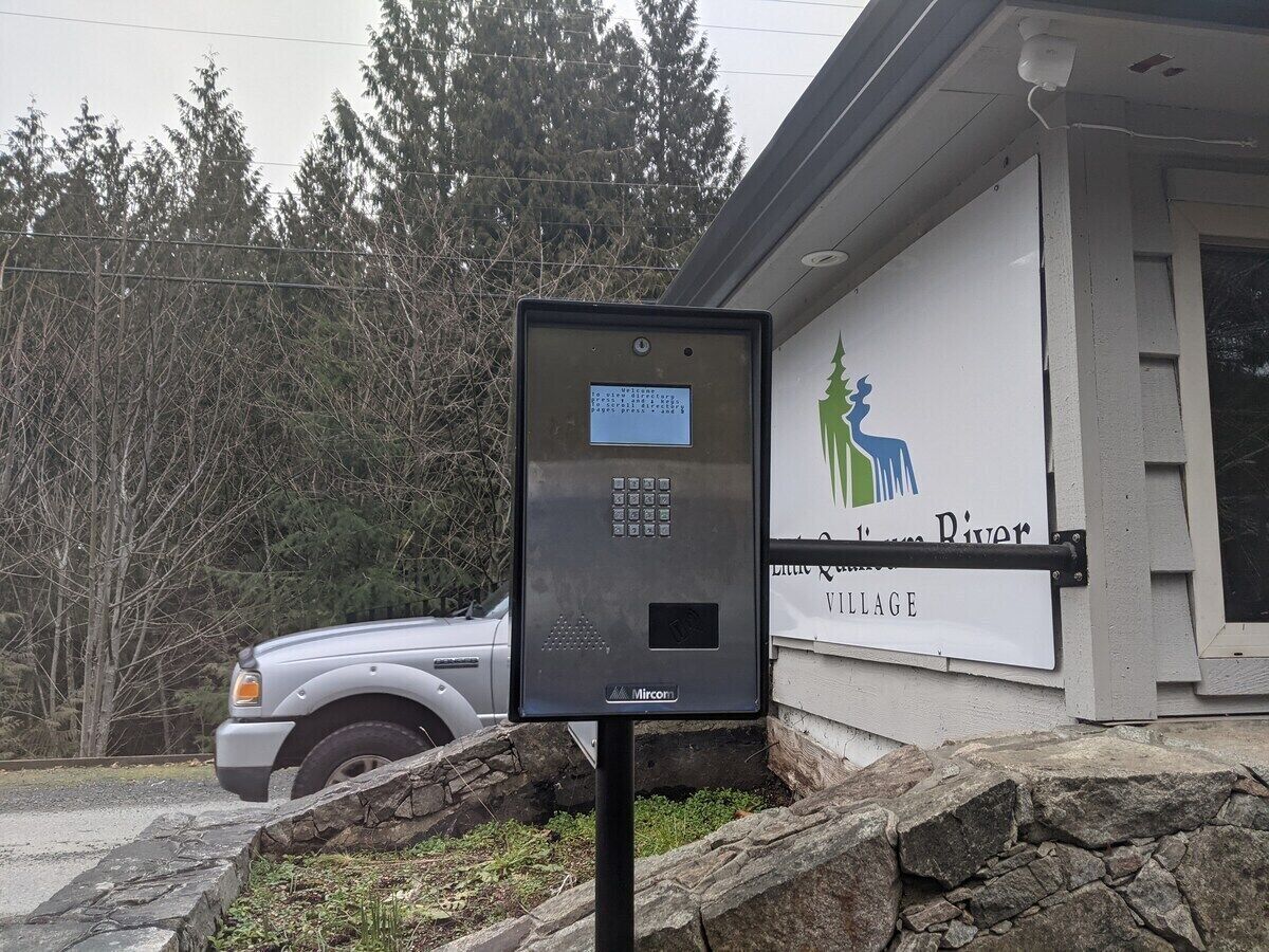 Ein Parkscheinautomat vor einem Gebäude mit einem Schild, auf dem 'Blue River Village' steht.