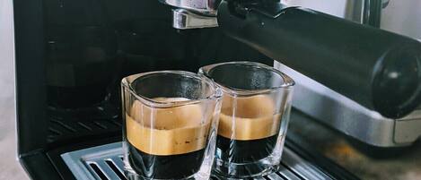 Una cafetera con dos tazas de café sobre la bandeja de goteo.