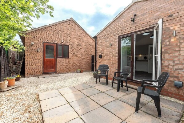 A patio area with a brick building, outdoor seating, and a gravel path.